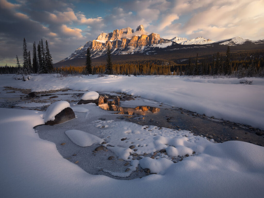 warm sunrise light over Castle Mountain during winter in Banff