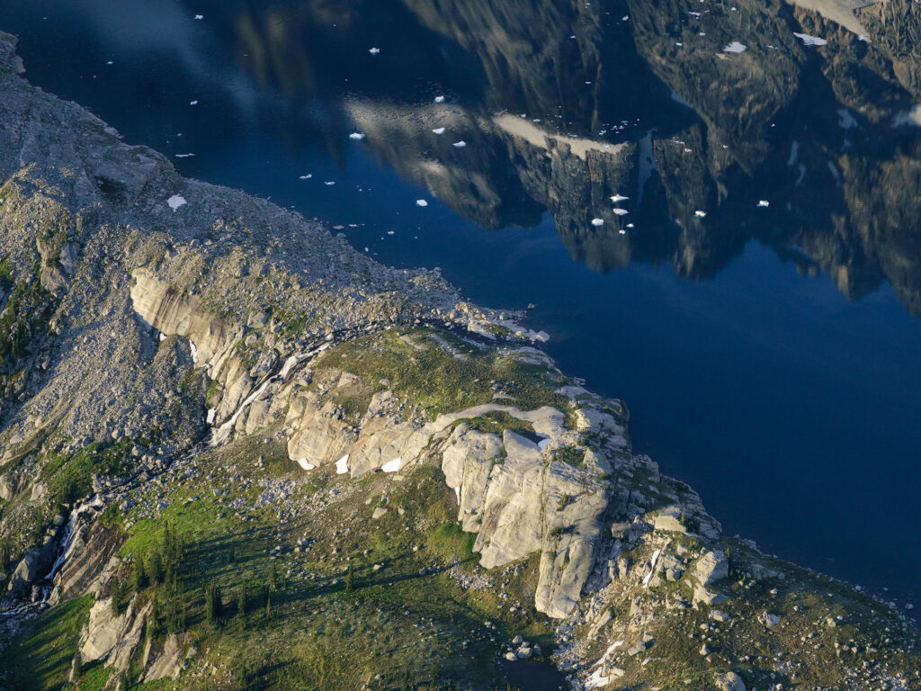 alpine lake with icebergs and waterfall reflect a dramatic mountain peak
