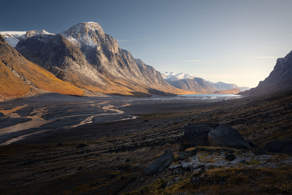 Reflected light illuminates streams under an arctic mountain