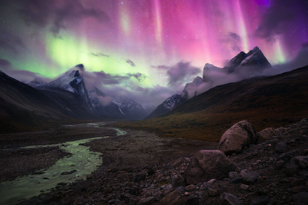bright aurora dances over arctic mountain peaks on Baffin Island