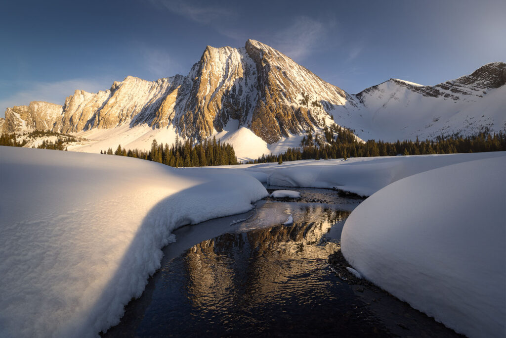 Golden light floods the winter landscape under a glowing and flowing mountain
